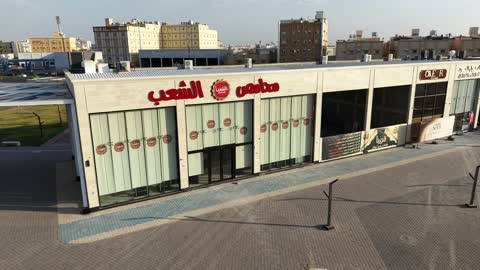 An entertainment and commercial center, featuring modern and advanced architectural design in the Kingdom of Saudi Arabia, with distinctive restaurants, cafes, and shopping centers. A drone shot of the My Walk complex on Amr Ibn Al-As Street in the Al-Musayf neighborhood of Tabuk city during the daytime, a place for shopping and having a good time.