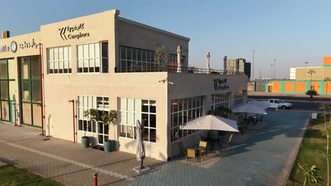 مركز ترفيهي وتجاري، الفن الهندسي المعماري على الطراز الحديث والمتطور في المملكة العربية السعودية، المطاعم والمقاهي والمراكز التجارية المميزة، تصوير درون لمجمع ماي ووك في شارع عمرو بن العاص في حي المصيف بمدينة تبوك في وقت النهار، مكان للتسوق وقضاء وقت ممتع