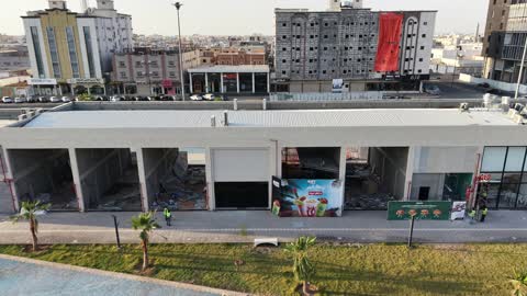 مركز ترفيهي وتجاري، الفن الهندسي المعماري على الطراز الحديث والمتطور في المملكة العربية السعودية، المطاعم والمقاهي والمراكز التجارية المميزة، تصوير درون لمجمع ماي ووك في شارع عمرو بن العاص في حي المصيف بمدينة تبوك في وقت النهار، مكان للتسوق وقضاء وقت ممتع