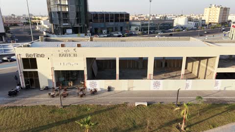 مكان للتسوق وقضاء وقت ممتع، مركز ترفيهي وتجاري، الفن الهندسي المعماري على الطراز الحديث والمتطور في المملكة العربية السعودية، المطاعم والمقاهي والمراكز التجارية المميزة، تصوير درون لمجمع ماي ووك في شارع عمرو بن العاص في حي المصيف بمدينة تبوك في وقت النهار