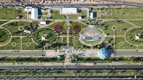 الفخر والاعتزاز بالانتماء الى الوطن,تصوير درون لسارية العلم السعودي الأخضر المرفرف في الهواء في مدينة تبوك،  المعالم المشهورة في المملكة العربية السعودية ،حركة مرور السيارات في شوارع المدينة