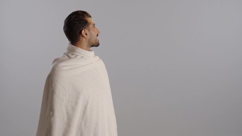الارتواء بماء زمزم، الحفاظ على الجسم من الجفاف، أداء مناسك الحج والعمرة، بورتريه مقرب لرجل عربي سعودي خليجي يرتدي زي الاحرام يقوم بشرب المياه العذب، خلفية رمادية