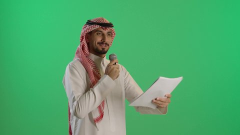 القاء محاضرة و اقامة ندوة، بورتريه لشاب عربي خليجي سعودي يرتدي الثوب التقليدي والشماغ  يحمل بيده مكبر الصوت وورقة بيضاء يقوم بإلقاء الخطاب بإيماءات الاندماج، خلفية خضراء، كروما