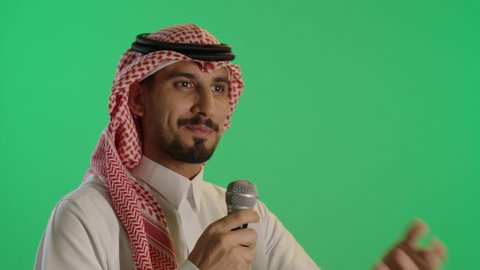 التواصل الفعال وتبادل الحواروالنقاش، بورتريه لشاب عربي خليجي سعودي يرتدي الثوب التقليدي والشماغ  يحمل بيده مكبر الصوت ويقوم بإلقاء الخطاب بإيماءات الاندماج، إقامة ورشة عمل ودورة تدريبية، خلفية خضراء، كروما