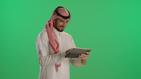 تصفح مواقع التواصل الاجتماعي, استخدام التكنولوجيا والتقنيات الحديثة، بورتريه لرجل عربي خليجي سعودي يرتدي الثوب التقليدي والشماغ يستخدم التابلت،  متابعة الأفلام والمسلسلات الممتعة، خلفية خضراء، كروما