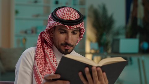 تعزيز مفهوم الثقافة والمعرفة ، تنمية المهارات الفكرية ، الاستمتاع بالهدوء والراحة داخل المنزل، قضاء الوقت بالمطالعة والثقافة، ممارسة الهوايات المفضلة، رجل عربي خليجي سعودي يرتدي الزى التقليدي و الشماغ يجلس على الأريكة يقوم بقراءة كتاب