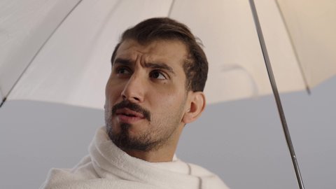 زيارة بيت الله الحرام في مكة المكرمة، بورتريه لرجل عربي خليجي سعودي يرتدي ملابس الاحرام يحمل بيده مظلة للحماية من أشعة الشمس و يقوم بشرب الماء، الركن الخامس من أركان الاسلام، آداء مناسك الحج والعمرة، خلفية رمادية