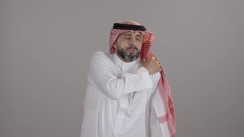 الأوجاع والآلام العصبية والعضلية، طلب المساعده والحاجه للعلاج، بورتريه لرجل عربي خليجي سعودى يرتدي الثوب التقليدي والشماغ يضع يده على كتفه بايماءات التعب والأرهاق، حالة اسعافية طارئة, خلفية بيضاء