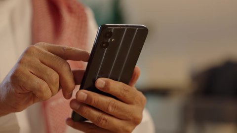 التواصل مع الأصدقاء، استخدام التطبيقات الحديثة و التسويق الألكتروني, رجل عربي خليجي سعودي يرتدي الثوب التقليدي والشماغ يستخدم الجوال, برامج التواصل الاجتماعي عبر الهاتف المحمول