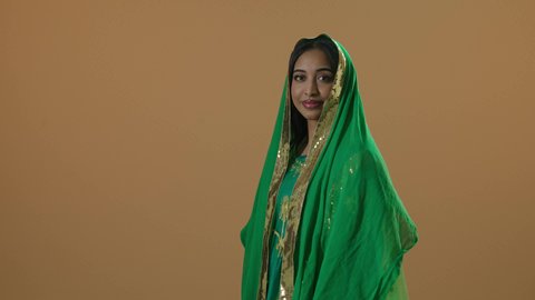 النظر إلى الكاميرا، ارتداء زي المنطقة الشرقية في المناسبات والأعياد الوطنية، يوم بدينا 1727 م، بورتريه لإمرأة عربية خليجية سعودية مبتسمة ترتدي الشيلة و البشت الأخضر في ذكرى تأسيس الدولة السعودية الأولى في 22 فبراير، صورة لكامل الجسم، خلفية بنية