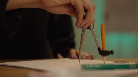 إكمال رسم مخطوطات البناء, مساهمة المرأة في تطور القطاع الهندسي, تصويرمقرب ليد مهندسة عربية خليجية سعودية تجلس على المكتب تمسك بيدها أدوات هندسية، متابعة استراتيجات المشروع