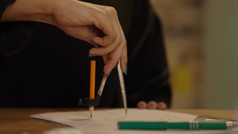 تخطيط وتنفيذ المشاريع الهندسية, مساهمة المرأة في تطورالقطاع الهندسي, تصويرمقرب ليد مهندسة عربية خليجية سعودية تجلس على المكتب تمسك بيدها أدوات هندسية لإكمال رسم المخطط المعماري، متابعة استراتيجات المشروع