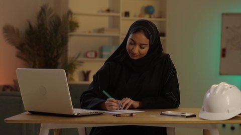 دراسه وتتبع المشاريع، مهندسة عربية خليجية سعودية محجبة ترتدي العباءة السوداء بجانبها خوذة الحماية تقوم بتدوين الملاحظات، متابعة المشاريع الإنشائية،مساهمة المرأة في تطور القطاع الهندسى