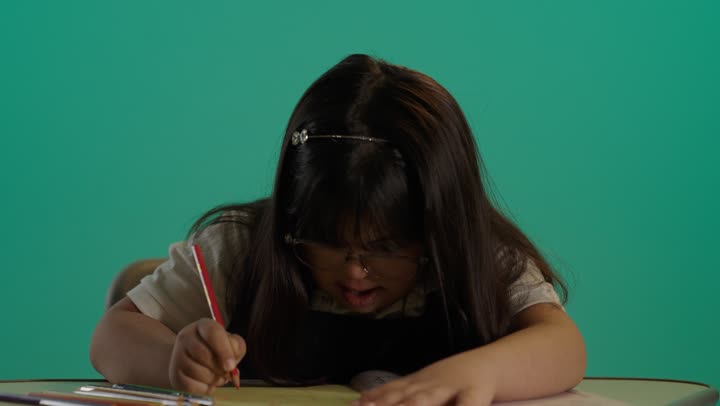 بورتريه لطفلة سعودية مصابة بمتلازمه داون تقوم بالرسم و التلوين بالألوان، إيماءات التركيز والاستمتاع، رعاية و تطوير مهارات الأطفال، قضاء وقت ممتع فى المنزل, خلفية خضراء