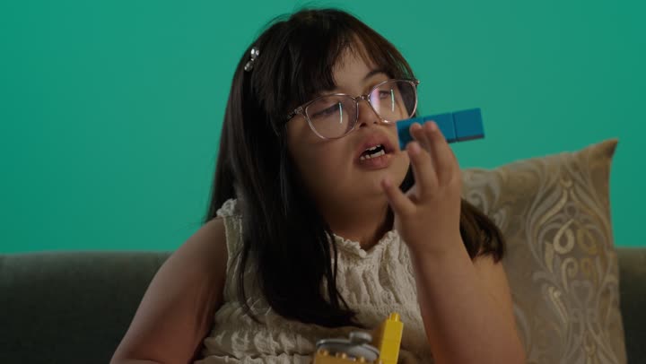 الابداع وتنمية التفكير، بورتريه لطفلة سعودية مصابة بمتلازمه داون ترتدى النظارة تمسك المكعبات، رعاية الموهبة والاهتمام بها فى السعودية، خلفية حضراء