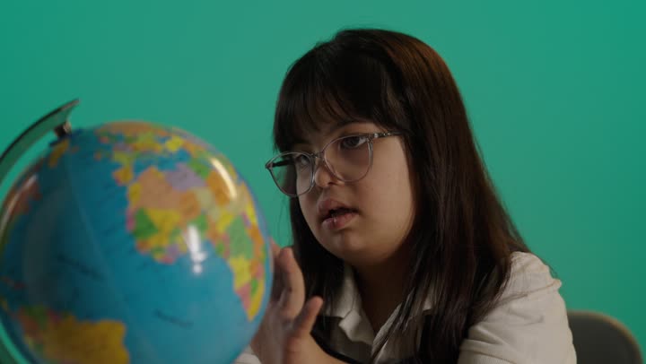 طفلة سعودية مصابة بمتلازمه داون ترتدى النظارة تحمل بيدها مجسم الكرة الارضية، مفهوم البحث والاستكشاف حول العالم، القيام برحلة سياحية