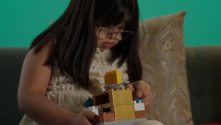 قضاء اوقات ممتعه فى المنزل، تنمية المهارات الذهنيه والفكريه، طفلة سعودية مصابة بمتلازمه داون يقوم باللعب بالمكعبات، مفهوم الاهتمام بالهوايات، تعابير السعاده والسرور