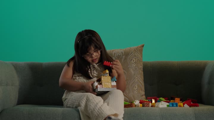 تنمية المهارات الذهنيه والفكريه، طفلة سعودية مصابة بمتلازمه داون يقوم باللعب بالمكعبات، مفهوم الاهتمام بالهوايات، قضاء اوقات ممتعه فى المنزل، تعابير السعاده والسرور