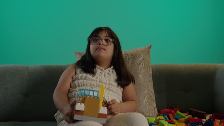 بورتريه لطفلة سعودية مصابة بمتلازمه داون ترتدى النظارة تمسك المكعبات، رعاية الموهبة والاهتمام بها فى السعودية، الابداع وتنمية التفكير، خلفية حضراء