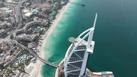 The architectural engineering art of buildings and skyscrapers in the Emirate of Dubai, aerial drone photography of the Burj Al Arab in the United Arab Emirates, famous tourist attractions, the economic and urban development of the state's facilities to attract tourists from all over the world, enjoying the calm atmosphere.