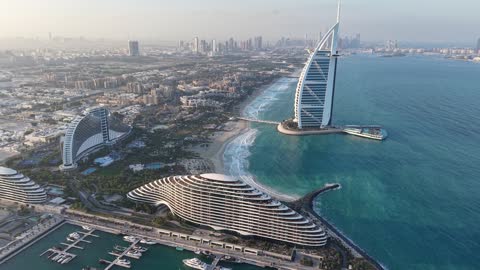 The architectural engineering art of buildings and skyscrapers in the Emirate of Dubai, aerial drone photography of the Burj Al Arab in the United Arab Emirates, famous tourist attractions, the economic and urban development of the state's facilities to attract tourists from all over the world, enjoying the calm atmosphere.