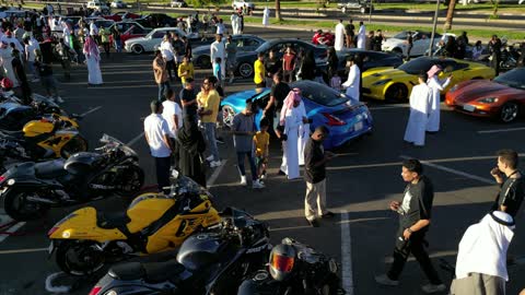 The movement of internal trade in the Kingdom of Saudi Arabia, attracting customers and consumers through a distinctive car display method, a market for buying and selling used cars, drone photography of rows of vehicles from various global brands in a car exhibition area in the Tabuk region.