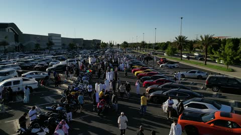 The movement of internal trade in the Kingdom of Saudi Arabia, attracting customers and consumers through a distinctive car display method, a market for buying and selling used cars, drone photography of rows of vehicles from various global brands in a car exhibition area in the Tabuk region.