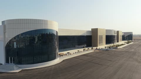 Improving and preparing economic buildings and facilities in the Kingdom of Saudi Arabia, drone photography of the Exhibition and Conference Center in Tabuk Province, main roads and streets, architectural engineering art in the modern style.