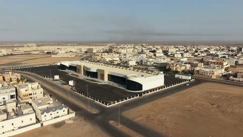 Improving and preparing economic buildings and facilities in the Kingdom of Saudi Arabia, drone photography of the Exhibition and Conference Center in Tabuk Province, main roads and streets, architectural engineering art in the modern style.