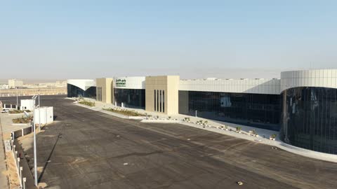 Improving and preparing economic buildings and facilities in the Kingdom of Saudi Arabia, drone photography of the Exhibition and Conference Center in Tabuk Province, main roads and streets, architectural engineering art in the modern style.