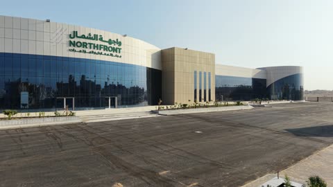 Improving and preparing economic buildings and facilities in the Kingdom of Saudi Arabia, drone photography of the Exhibition and Conference Center in Tabuk Province, main roads and streets, architectural engineering art in the modern style.