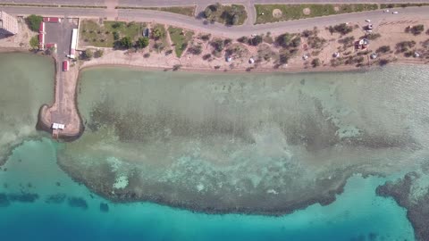 لون المياه البحر الفيروية، من أكبر محافظات تبوك من حيث المساحة، مركزاً تجارياً هاماً بعد مكة المكرمة، الموقع على ساحل البحر الأحمر بين مدينتي الوجه وينبع، أملج الساحلية في السعودية،  تصوير درون لمياه البحر في أملج في المملكة العربية السعودية