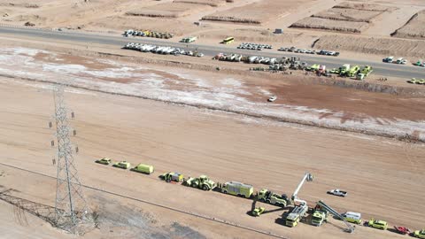 تدريباً أو مناورة طوارئ طبية في الهواء الطلق، المعدات سيارة إسعافر، مخاريط مرورية لتنظيم الموقع، أفراد يرتدون زي المسعفين والأطباء،  تنظمها هيئة الهلال الأحمرفي المملكة العربية  السعودية أو جهة حكومية أخرى في المملكة العربية السعودية،  التعاون بين جهات متعددة