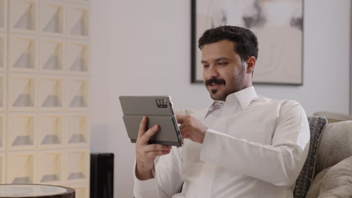 التطور و التكنولوجيا الحديثة، ادارة الأعمال عن بعد، رجل عربي خليجي سعودي يرتدي الثوب التقليدي يستخدم التابلت، وظائف ومهن سعودية