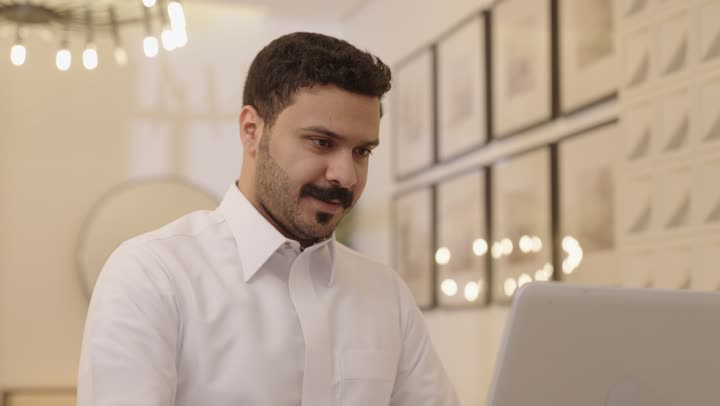 ادارة الأعمال عن بعد، إنجاز المهام المطلوبة عبر اللابتوب، التطوروالتكنولوجيا الحديثة، رجل عربي خليجي سعودي يرتدي الثوب التقليدي يستخدم الحاسوب المحمول، وظائف ومهن سعودية
