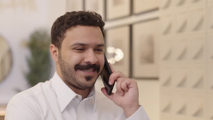 Making a phone call using a mobile phone, an Arab Gulf Saudi man wearing traditional attire uses his phone, chatting with family and friends, having a good time.