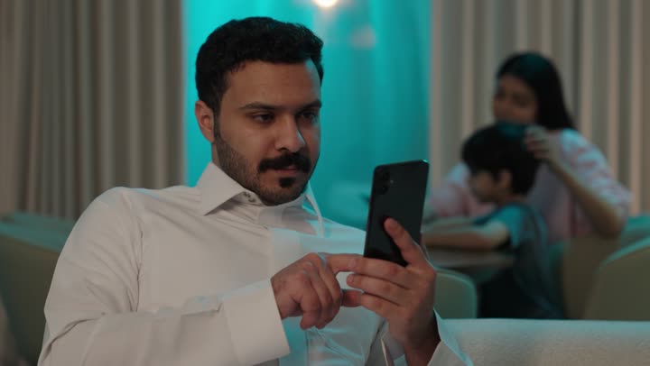 استخدام الأجهزة التقنية الحديثة و المتطورة، التواصل مع الأصدقاء، تصفح وسائل التواصل الاجتماعي عبر الجوال, رجل عربي خليجي سعودي يرتدي الثوب التقليدي يمسك الهاتف المحمول بيده