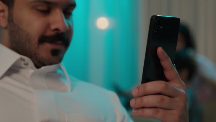 التواصل مع الأصدقاء، تصفح وسائل التواصل الاجتماعي عبر الجوال, استخدام الأجهزة التقنية الحديثة و المتطورة, رجل عربي خليجي سعودي يرتدي الثوب التقليدي يمسك الهاتف المحمول بيده