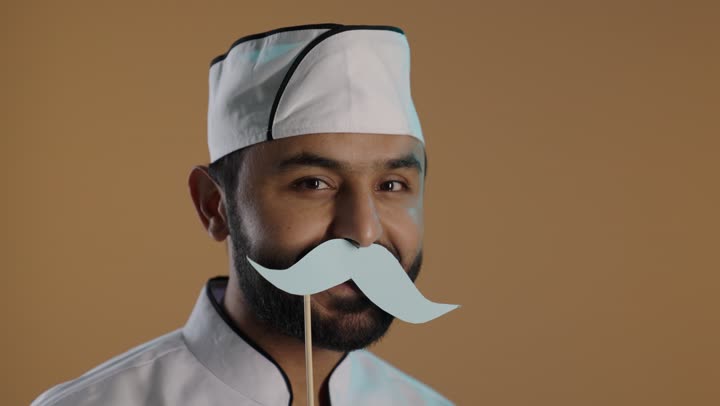 الدور الفعال للرجال في المجتمع, الاحتفال السنوي باليوم العالمي للرجال ١٩ نوفمبر، بورتريه لرجل عربى خليجي سعودى يرتدي الزي الرسمي الخاص بمزاولة مهنة الطباخ يمسك بيده عود خشبي مع قصاصة ورقية على شكل شارب، خلفية بنية