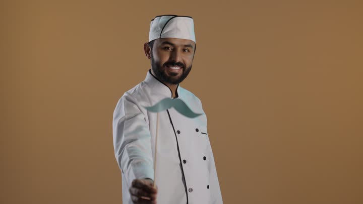 ايماءات السعادة والسرور, الاحتفال السنوي باليوم العالمي للرجال ١٩ نوفمبر، بورتريه لرجل عربى خليجي سعودى يرتدي الزي الرسمي الخاص بمزاولة مهنة الطباخ يمسك بيده عود خشبي مع قصاصة ورقية على شكل شارب، خلفية بنية