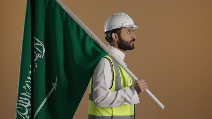 التباهي بإنجازات البلاد، اليوم الوطني السعودي 23 سبتمبر، بورتريه لمهندس عربي خليجي سعودي يرتدي سترة واقية وخوذة السلامة يحمل علم المملكة على كتفه، مهن ووظائف سعودية، خلفية بنية
