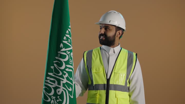 بورتريه لمهندس عربي خليجي سعودي يرتدي سترة واقية وخوذة السلامة، يحتفل باليوم الوطني السعودي، مهن ووظائف سعودية، اليوم الوطني السعودي ، خلفية بنية