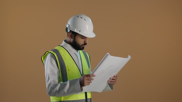 مفهوم الهندسة وأعمال البناء, النظر والتدقيق في مخططات الإنشاءات, بورتريه لمهندس عربي خليجي سعودى يرتدي الثوب التقليدي والستره الوقائيه ويضع خوذه الحماية على رأسه يقوم بدراسه وتصفح المخططات الهندسيه، تنمية وتطويرو متابعة الأعمال الهندسيه، خلفية بنية