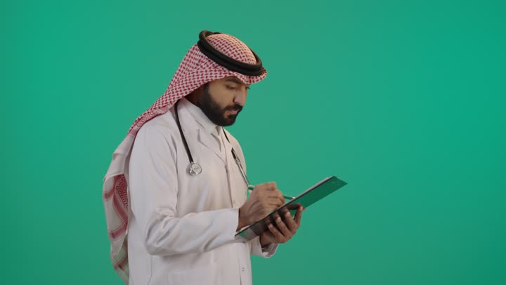 تدوين وتسجيل معلومات وملفات المرضى, مفهوم الرعاية الصحية في السعودية، بورتريه لطبيب عربي خليجي سعودي يرتدي الثوب التقليدي والشماغ مع المعطف الأبيض يضع سماعة الفحص و يقوم بالكتابة على ملف, تقديم الخدمات العلاجية في المراكز الطبية والمستشفيات, خلفية خضراء