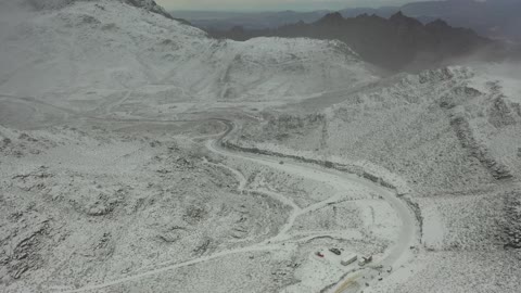 أجواء ثلجية باردة، موقع أثري جغرافي متميز، سلسلة جبال اللوز في منطقة تروجينا تكسوها الثلوج، جبال منحوتة وتشكيلات جبلية في مدينة تبوك، معالم حضارية سياحية في المملكة العربية السعودية، تصوير درون جوي للتكوينات الصخرية في قرية بجدة نيوم غرب المملكة العربية السعودية