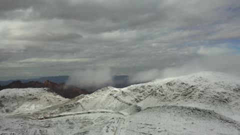 موقع أثري جغرافي متميز، سلسلة جبال اللوز في منطقة تروجينا تكسوها الثلوج، جبال منحوتة وتشكيلات جبلية في مدينة تبوك، معالم حضارية سياحية في المملكة العربية السعودية، تصوير درون جوي للتكوينات الصخرية في قرية بجدة نيوم غرب المملكة العربية السعودية