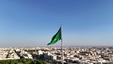 Famous tourist attractions in Tabuk, the tallest flagpole in the world in Tabuk, Saudi National Day, aerial drone footage of the largest flagpole in the city of Tabuk in the Kingdom of Saudi Arabia, traffic movement, roads and streets of Tabuk, the model of the official emblem of the Kingdom of Saudi Arabia in Tabuk Square.