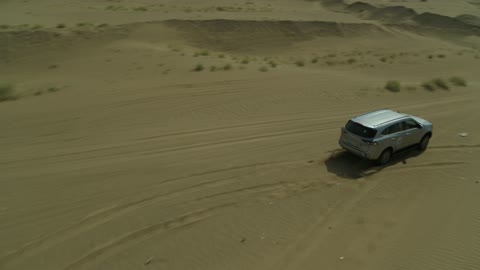 Recreational activities for driving cars in desert areas, a safari adventure on the sand dunes in the Kingdom of Saudi Arabia, drone photography of an Isuzu off-road vehicle on the golden desert sands, sand hills, and rock formations in the Arab deserts.