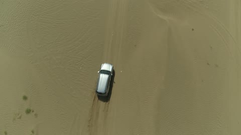الأنشطة الترفيهية لقيادة السيارات في المناطق الصحراوية، مغامرة سفاري على الكثبان الرملية في المملكة العربية السعودية, تصوير درون لسيارة ايسوزو ذات الدفع الرباعي الجبلية على رمال الصحراء الذهبية , التلال الرملية والتشكيلات والتكوينات الصخرية في الصحارى العربية