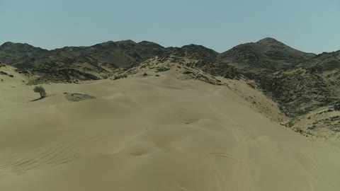 The sand dunes and rock formations in the Arab deserts, recreational activities for driving cars in desert areas, a safari adventure on the sand dunes in the Kingdom of Saudi Arabia, drone photography of an Isuzu off-road vehicle on the golden desert sands.